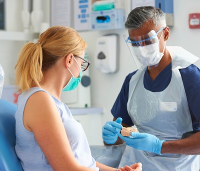 Dentist showing patient in-chair a model of teeth.