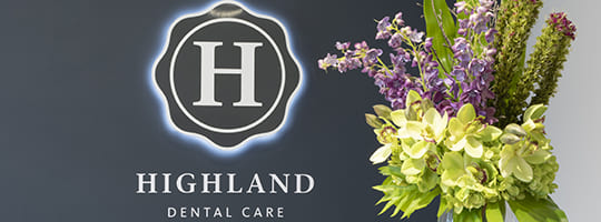 Logo and name of Highland Dental Care displayed on a wall in the dentists