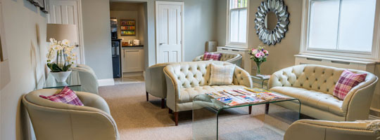 The comfortable patient lounge at the Raglan Suite with plush white sofas and magazines