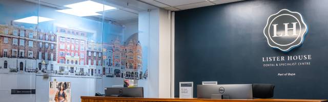 The reception desk at Lister House has a glass wall with views out onto artwork showing a street of colourful houses