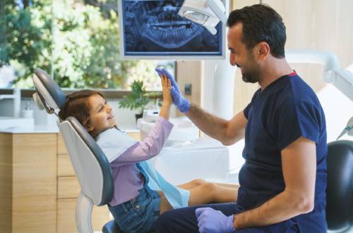 A young girl high fiving a dentist after their appointment