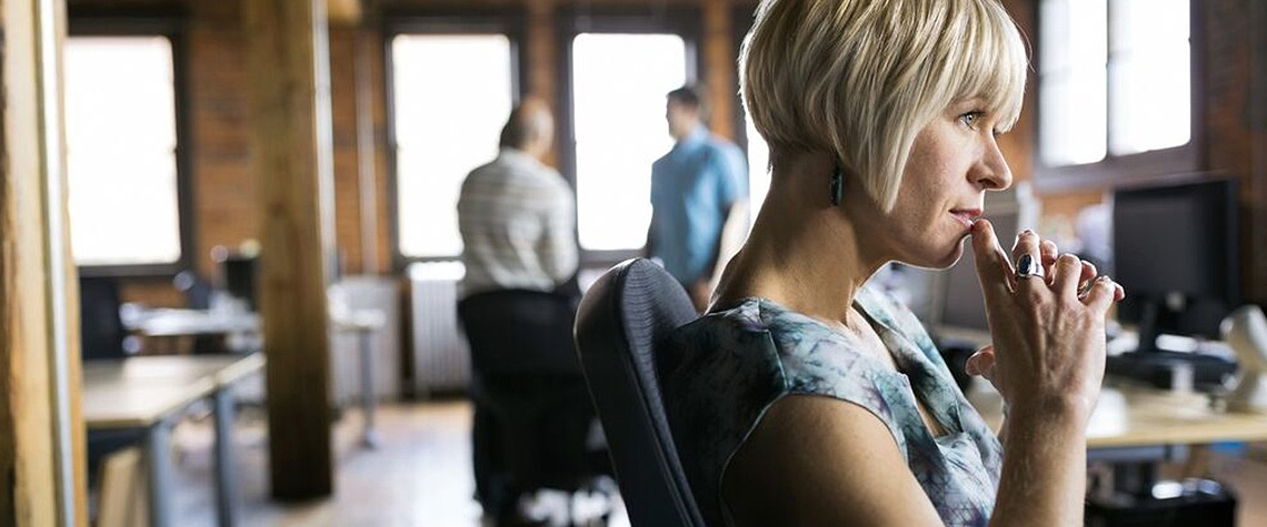 Office employee at desk in modern workspace with colleagues in background, focus and workplace environment