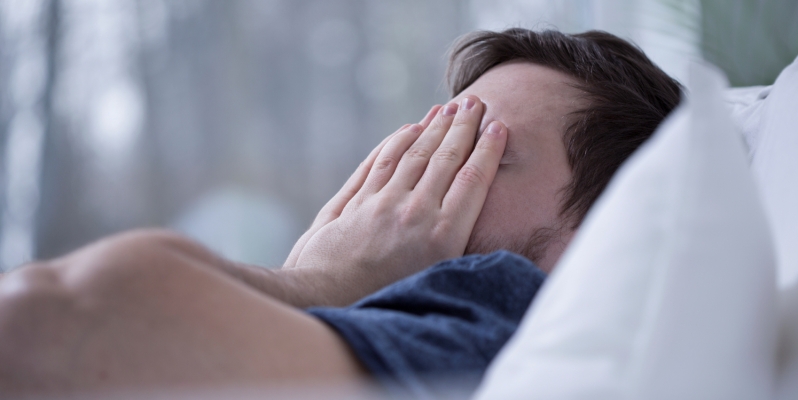 A man who can't sleep, holding his head