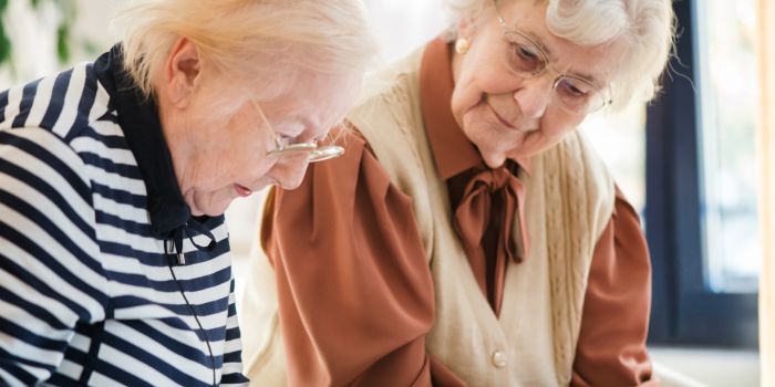 Two elderly women reading the paper