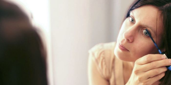 Woman looking in the mirror as she applies mascara