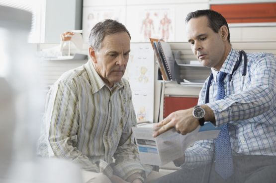 A doctor showing a senior patient a leaflet in his office